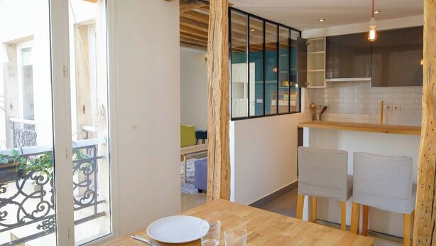 Un comedor con una mesa de madera, dos sillas y un vaso de agua.