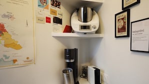 Un coin cuisine équipé d’une machine à café, d’une bouilloire et d’un moulin à café, le tout posé sur le plan de travail.