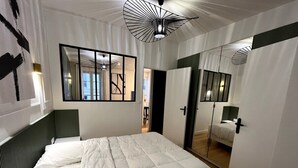Un dormitorio con una cama grande, un espejo y una puerta que da a otra habitación.