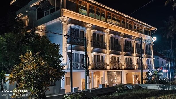 Un edificio a più piani con balconi, ampie finestre e una facciata ben illuminata di notte.