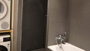 A modern bathroom with a built-in washing machine, a shower enclosure, and a bathtub. - Beautiful apartment 4 ppl. / Pigalle - Montmartre (Paris)