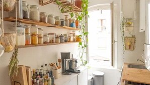 Een keuken met houten planken, hangmanden en een raam.