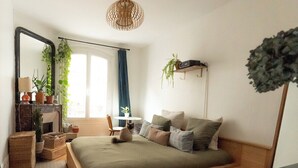 Een gezellige slaapkamer met een houten bed, een nachtkastje, een spiegel en een hangplant.