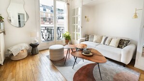 A modern living room with a white sofa, a wooden coffee table, and a large mirror on the wall. - Very bright. 1 bedroom Batignolles / Opera. (Paris)
