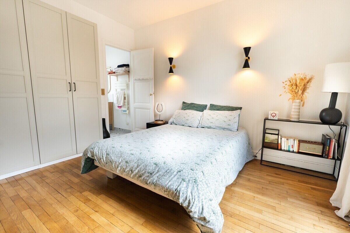 Une chambre à coucher comprenant un lit, des tables de chevet, une armoire et une bibliothèque.