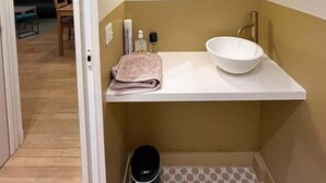 A modern bathroom with a white sink, a mirror, and a towel on the counter. - Beautiful Renovated Apartment in Le Marais (Paris)