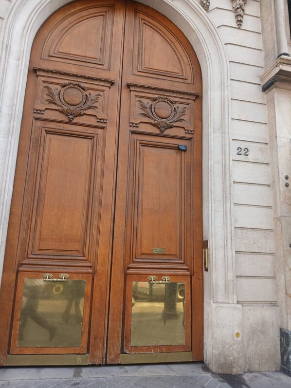 A double wooden door with glass panels and a brass plaque, number 22 on the wall beside it.