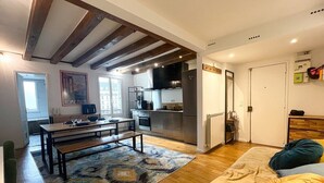A modern kitchen with a dining area, wooden flooring, and a bench. - Spacious apartment in Batignolles (Paris)