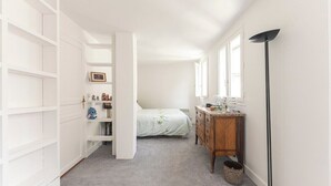 A narrow hallway leading to a bedroom with a bed, a dresser, and a wardrobe. - Spacious | in the Heart of the Marais | 4 people (Paris)