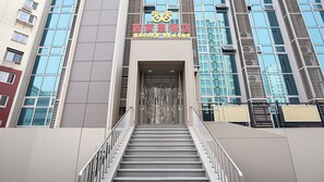 A hotel entrance with a staircase leading up to a glass door, surrounded by modern buildings. - Xixili Hotel - Beijing West Station Store (Beijing)