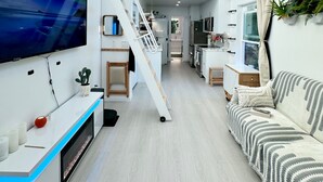 Ein modernes, kompaktes Wohnzimmer mit Küche, Essbereich und einer Couch.