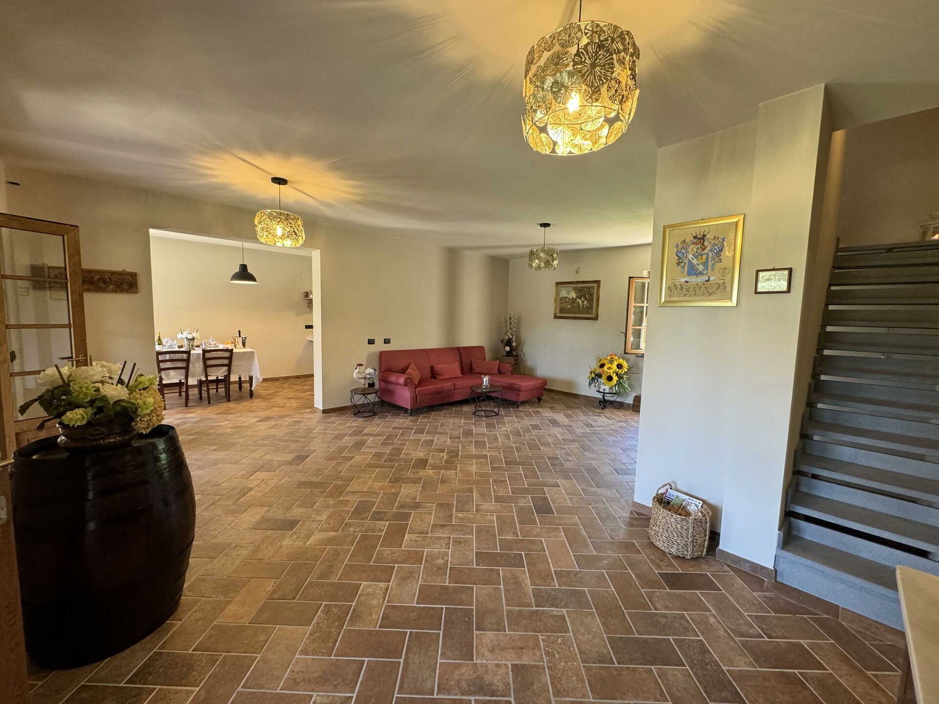 Een ruime woonkamer met een visgraatvloer, een rode bank en twee hanglampen.