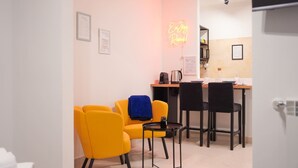 Una habitación moderna con sillas amarillas, una mesita y una cocina al fondo.