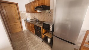 A kitchen with wooden cabinets, a stainless steel refrigerator, a built-in oven, and a microwave. - Las Floritas 5 - Plumeria (Playa de Las Americas)