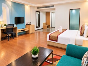 A modern hotel room with a bed, desk, chair, TV, and a small plant. - The Altruist Wagholi Hotel (Pune)