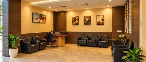 A reception area with a reception desk, several leather chairs, and potted plants.