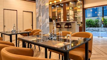 Un comedor de hotel con mesas preparadas para cuatro personas, equipado con cristalería y cubiertos.