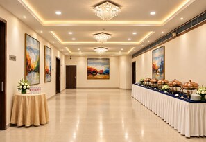 A hotel corridor with a buffet table, artwork on the walls, and a chandelier. - The Altruist Wagholi Hotel (Pune)