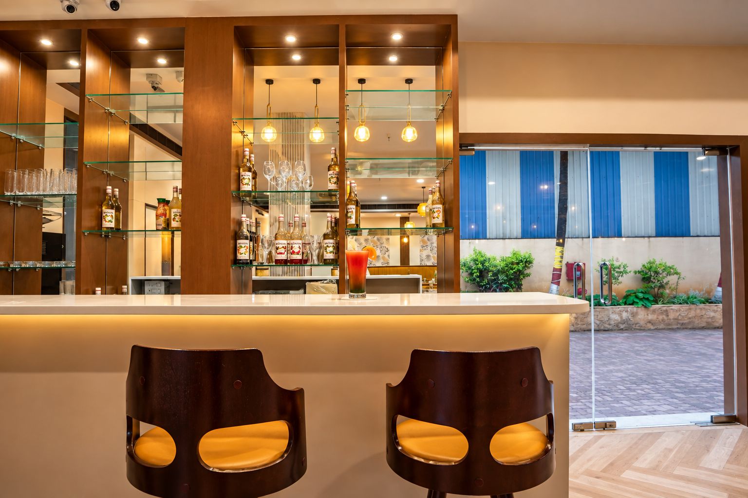 Una zona de bar con mostrador, taburetes y vistas al exterior.