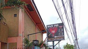 Un bâtiment sur lequel est apposée une enseigne publicitaire pour un hôtel appelé WJY Inn, avec un symbole en forme de cœur et un prix de 199 pesos.