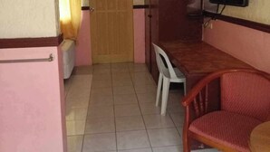 Une petite pièce, de taille modeste, comprenant un lit, un bureau, une chaise et un téléviseur.