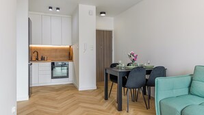 A compact living space with a kitchenette, dining area, and a teal sofa.