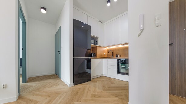 A modern kitchen with white cabinets, a wooden countertop, and a built-in oven.