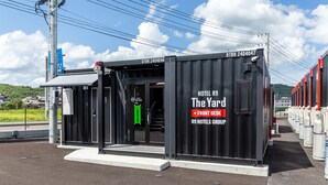 A black container-style building labeled "The Yard" with "R9 Hotels Group" and "Front Desk" signage. - HOTEL R9 The Yard Usa (Usa)