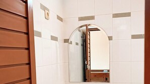 Un baño con un lavamanos blanco, un espejo y una puerta de madera.