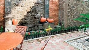 Un patio al aire libre con pared de piedra, una pequeña cascada y plantas en macetas.