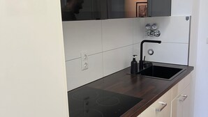 Et moderne køkken med en mørk bordplade, hvide skabe og en sort armatur.