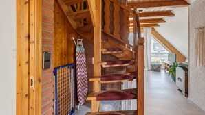 Una escalera de madera con cojines rojos, una pared de ladrillo y vista a una zona de cocina.