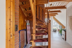 Una escalera de madera con cojines rojos, una pared de ladrillo y vista a una zona de cocina.