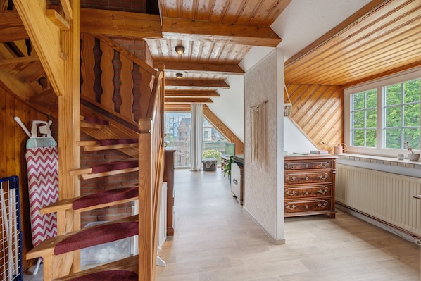 A wooden staircase leading to a loft bedroom with a view of the outside.
