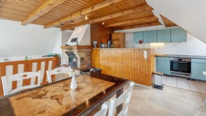 Una cocina con vigas de madera en el techo, una mesa de comedor con sillas, pared de ladrillo y salpicadero de azulejos.