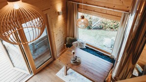 A wooden interior with a table, hanging light, and a view of the outdoors.