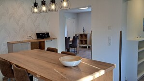 A modern kitchen with a wooden table, a bowl, and pendant lights. - Apartment 'Ferienwohnung Ebbe' with Shared Garden, Balcony and Wi-Fi (Pellworm)