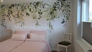 A bedroom with a bed, pillows, a chair, and a window with blinds. - Apartment 'Ferienwohnung Ebbe' with Shared Garden, Balcony and Wi-Fi (Pellworm)