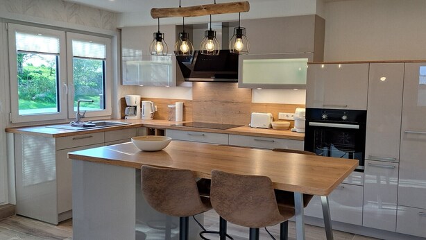 A modern kitchen with a central island, wooden countertops, and pendant lighting. - Apartment 'Ferienwohnung Ebbe' with Shared Garden, Balcony and Wi-Fi (Pellworm)