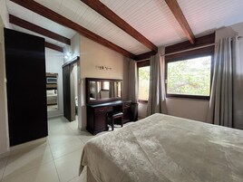A bedroom with a bed, a dresser, a mirror, and a window with curtains.