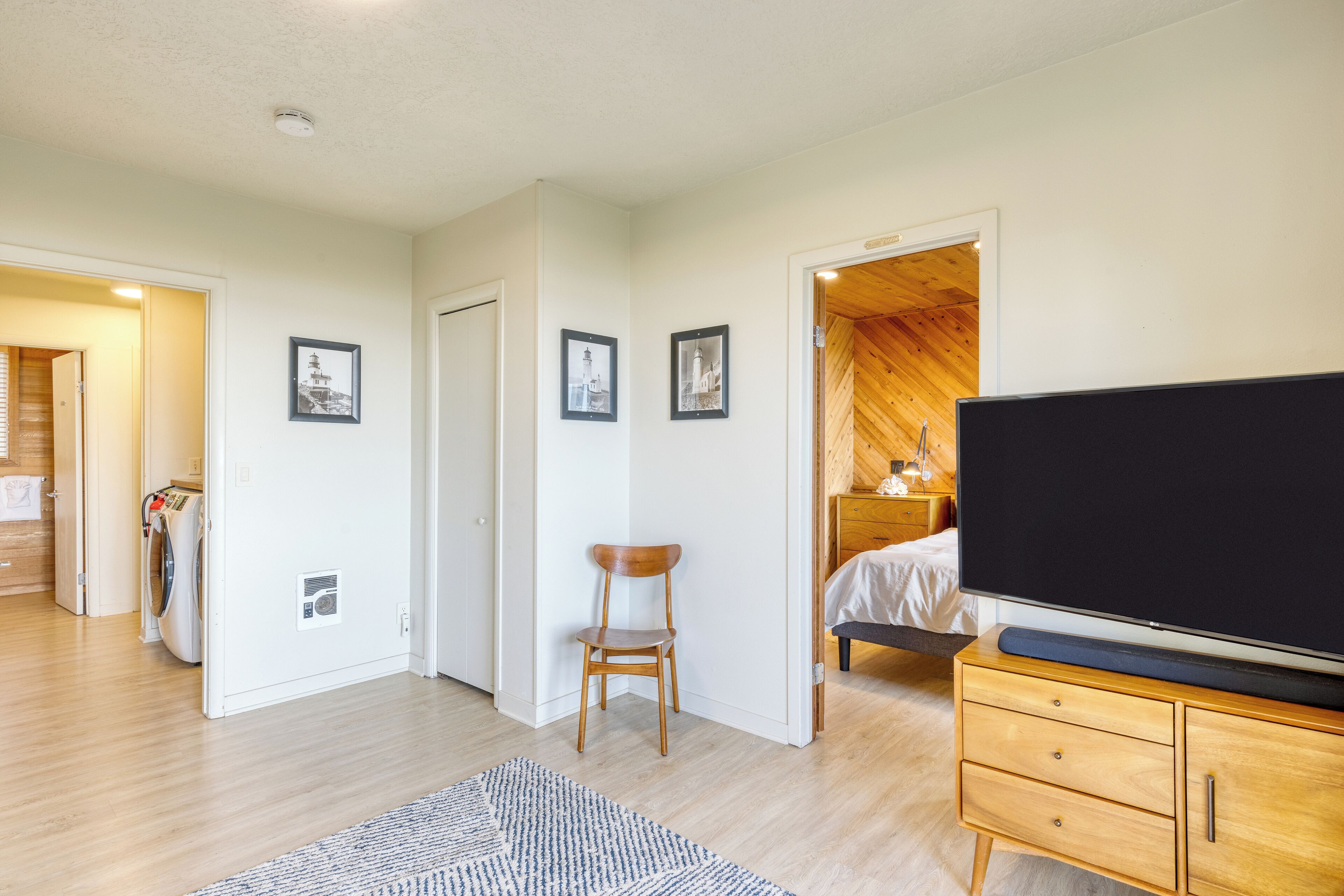 A bedroom with a bed, a TV, a wooden dresser, and a chair.