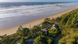 Ein Küsteneigentum mit Blick auf den Strand, ein kleines Haus und üppiges Grün.
