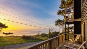 Eine Holzterrasse mit Stühlen, die einen malerischen Blick auf das Meer bei Sonnenuntergang bietet.
