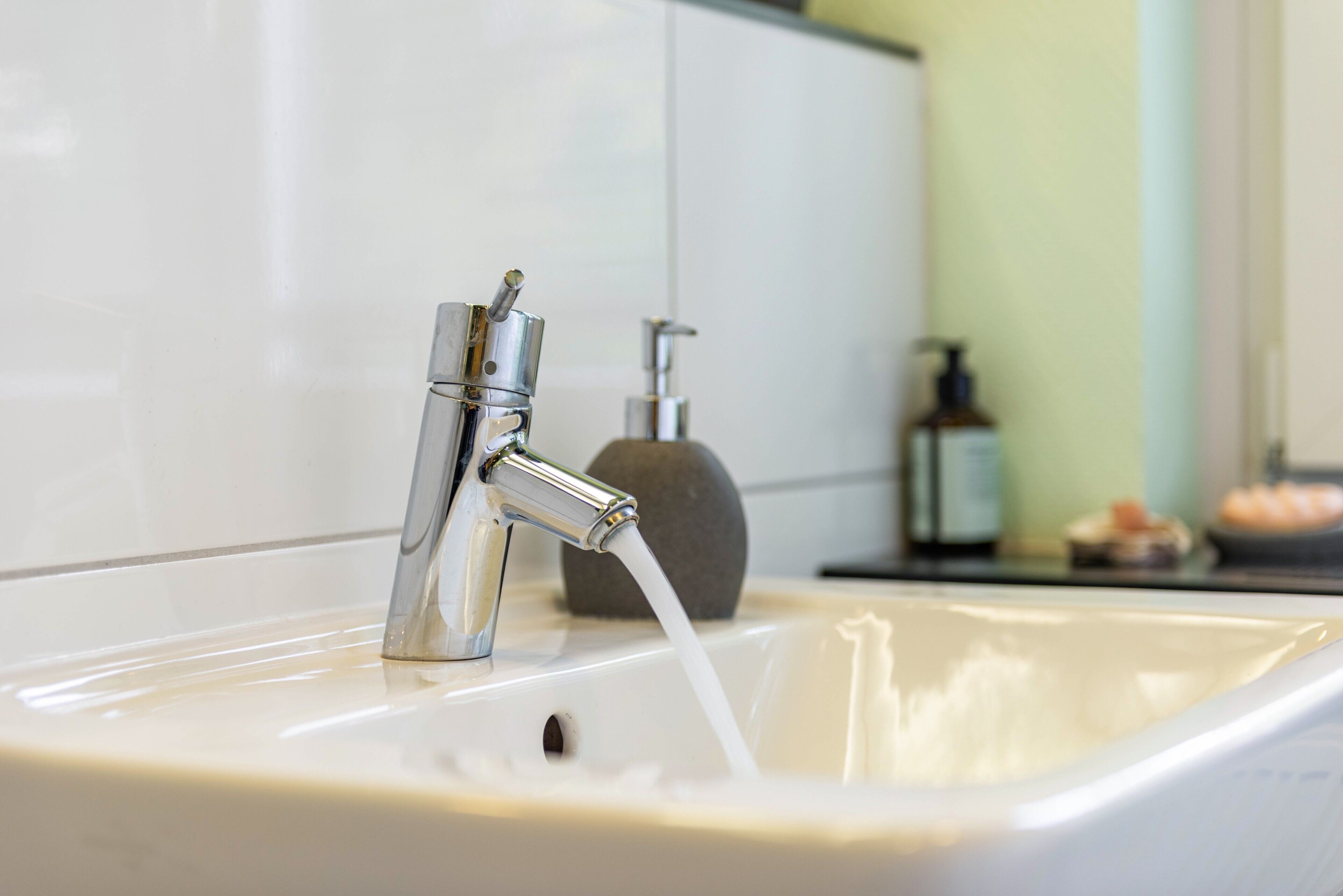 A bathroom sink with a chrome faucet and a soap dispenser.
