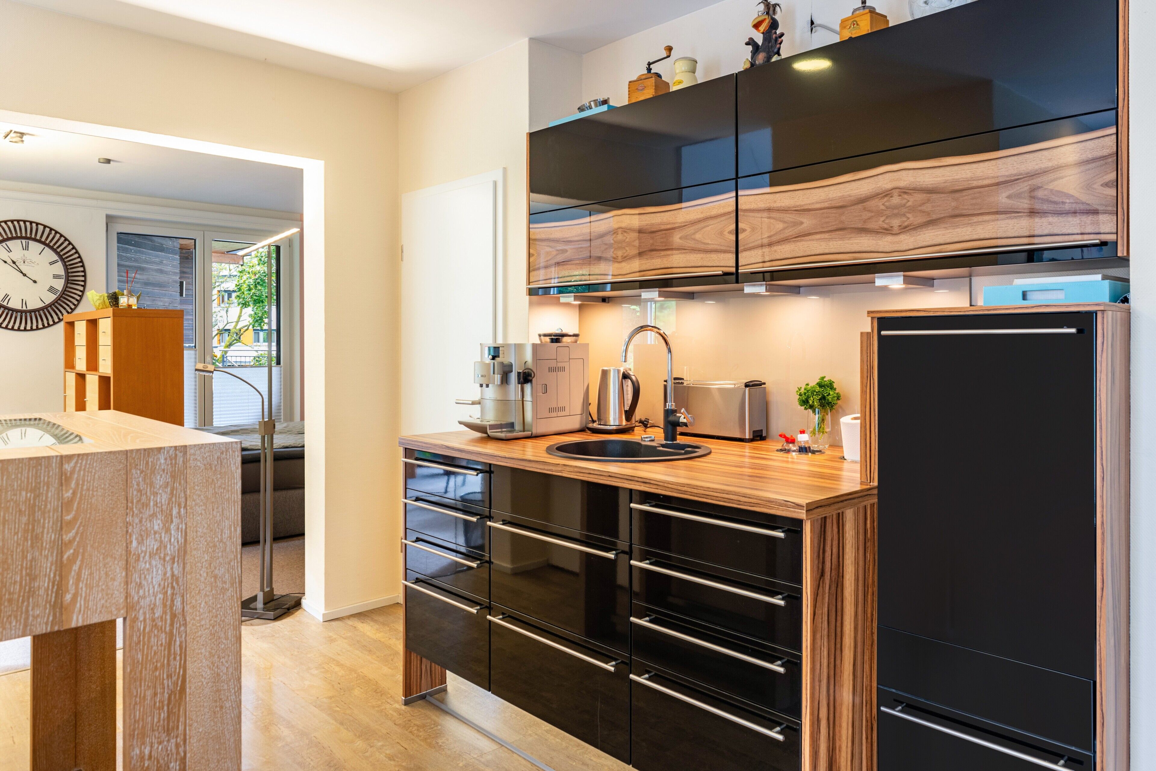 A modern kitchen with a wooden countertop, black cabinetry, and a built-in oven.