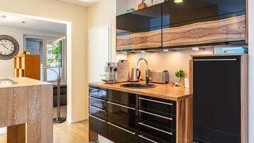 A modern kitchen with a wooden countertop, black cabinetry, and a built-in oven.
