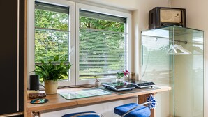 Eine Küche mit Holzarbeitsplatte, zwei blauen Barhocker, einem Glaskabinett und einem Fenster mit Jalousien.