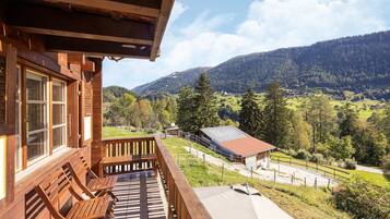 Une cabane en bois dotée d’un balcon donnant sur un paysage montagneux.