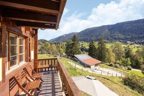 A wooden cabin with a balcony overlooking a mountainous landscape.