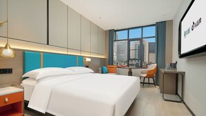 Una habitación de hotel moderna con una cama grande, un escritorio y vistas a la ciudad.